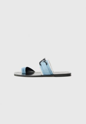 Sandali slide in denim blu con suola nera, caratterizzati da due larghe cinghie e un distintivo dettaglio a clip sulla cinghia. Design piatto e stile aperto sulla punta.
