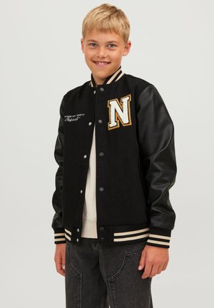 Giacca varsity nera con maniche in pelle, coste a righe crema, ricamo dorato "N" sul petto e testo cucito bianco.