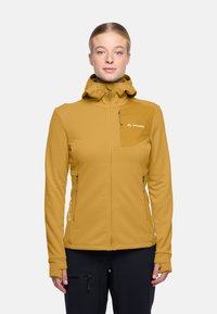 Giacca softshell gialla con cappuccio, tasche con zip e aperture per il pollice. Presenta un design aderente e un logo sul petto.