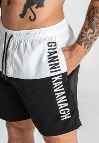 Crno-bijeli kupaće ga�će s elastičnom trakicom, s bočnim džepom i vertikalnim logotipom "GIANNI KAVANAGH" u bijeloj boji.
