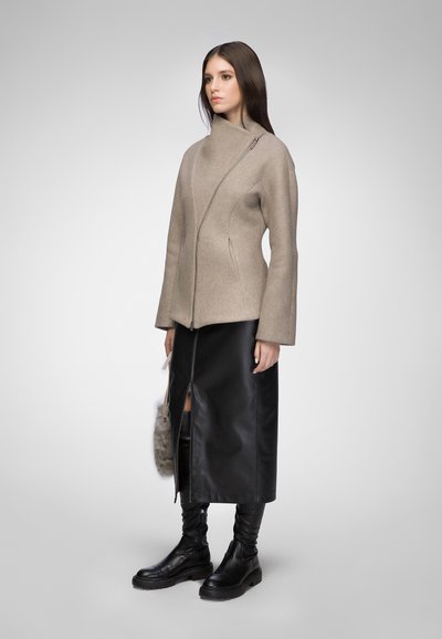 Beige wool blend coat with diagonal zipper, long sleeves, paired with a black leather skirt featuring a front slit and knee-high black boots.