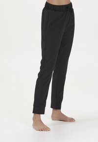 Svarta byxor med elastiskt midjeband, snörning och sidofickor. Torr design med uppvikta muddar, tillverkade av mjukt, lätt tyg.