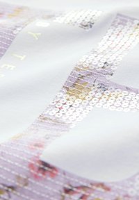 Bijela tkanina sa sequin dizajnom u nijansama ljubičaste i zlatne boje, s cvjetnim uzorcima. Tekstura je glatka s sjajnim završetkom.