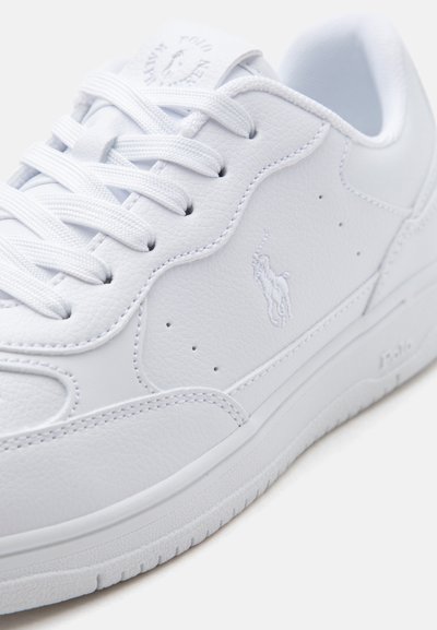 Λευκό δερμάτινο αθλητικό παπούτσι με κεντημένο λογότυπο, λευκά κορδόνια και υφασμένη σόλα, που δείχνει πλάγια και από πάνω λεπτομέρειες σε ουδέτερο φόντο.