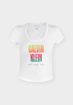 Biały krótki crop top Calvin Klein z wielokolorowym napisem "CALVIN KLEIN" i dodatkowym małym napisem poniżej na jednolitym białym tle.