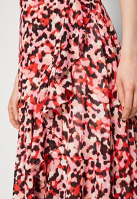 Skjorta med ett livfullt mönster i röd, rosa och svart leopardtryck. Har volangdetaljer längs fållen och en lätt, flödande textur.