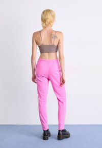 Rjava žametna bralette in roza trenirka z elastičnim pasom; črne platform škornje; model obrnjena stran, ki prikazuje obleko.