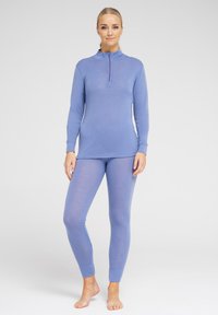 Langærmet lyseblå top med kvart lynlås-krave, parret med matchende tætsiddende leggings; blødt, strækbart stof, minimal detaljer.