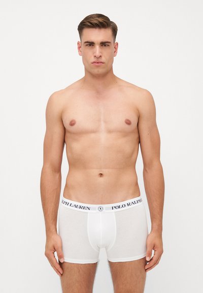 Fehér pamut boxer alsónadrág fekete derékpánttal, amelyen a "POLO RALPH LAUREN" felirat szerepel. Zökkenőmentes textúra és testhezálló kialakítás. A modellen felső nélkül látható.