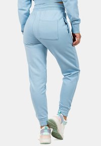 Lichtblauwe joggingbroek met een eenvoudig ontwerp, geribbelde tailleband, zijzakken en snugge boorden, gedragen met multicolore sportschoenen.