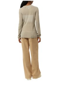 Gestreepte lange mouwen top in beige en wit, met een relaxte pasvorm en een ronde zoom. Gecombineerd met brede beige broek.