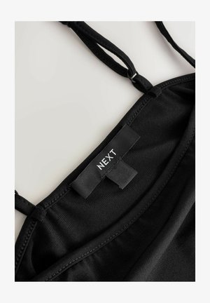 Schwarzes ärmelloses Oberteil mit verstellbaren Trägern und eingenähtem Etikett mit der Aufschrift "NEXT" am inneren Kragen.