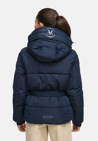 Námornícka pufrová bunda s kapucňou, opaskom v páse a logom na golieri. Obsahuje prešívanú textúru a mäkký materiál pre teplo.
