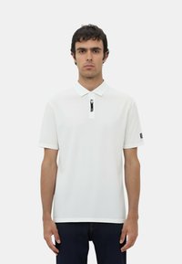 Polo shirt bianco con colletto a zip e maniche corte, caratterizzato da un'etichetta sulla zip e un bordo a contrasto sulle maniche.