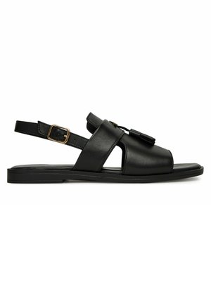 Czarny skórzany sandał na pasku z tyłu z detalem w postaci frędzli, otwartymi bokami, złotą klamrą i płaską podeszwą.