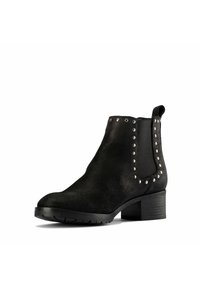 Botas de tobillo de ante negro con puntera redondeada, paneles laterales elásticos y tachuelas plateadas a lo largo de las costuras. Tacón bloque grueso para mayor estabilidad.
