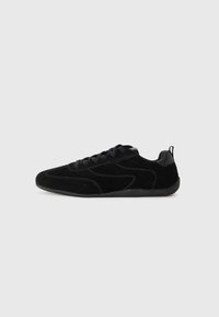 Sneaker in suede nero con finitura testurizzata, caratterizzati da una silhouette elegante, lacci neri e suola in gomma. Tra gli accessori c'è un pannello sul retro per una presa migliore.