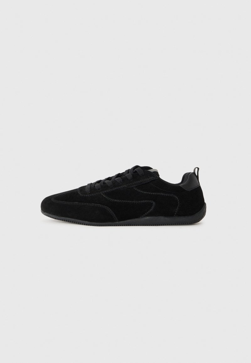 Sneaker in suede nero con finitura testurizzata, caratterizzati da una silhouette elegante, lacci neri e suola in gomma. Tra gli accessori c'è un pannello sul retro per una presa migliore.