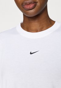 Λευκό βαμβακερό μπλουζάκι με μαύρο λογότυπο Nike στο στήθος. Απλός σχεδιασμός με λαιμόκοψη τύπου κρου και κανονική εφαρμογή. Ομαλή υφή.