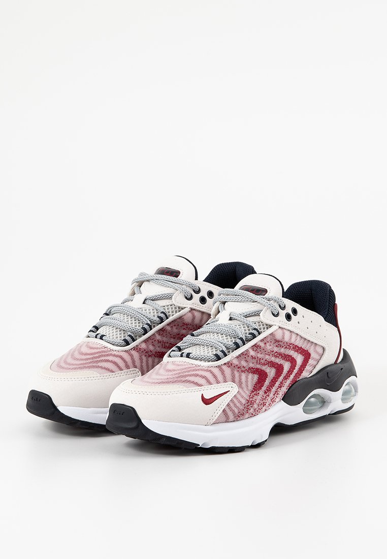 Sneakers da uomo con upper beige chiaro caratterizzati da motivi a onde rossi, lacci grigi, dettagli blu navy e suola bianca con ammortizzazione ad aria visibile.