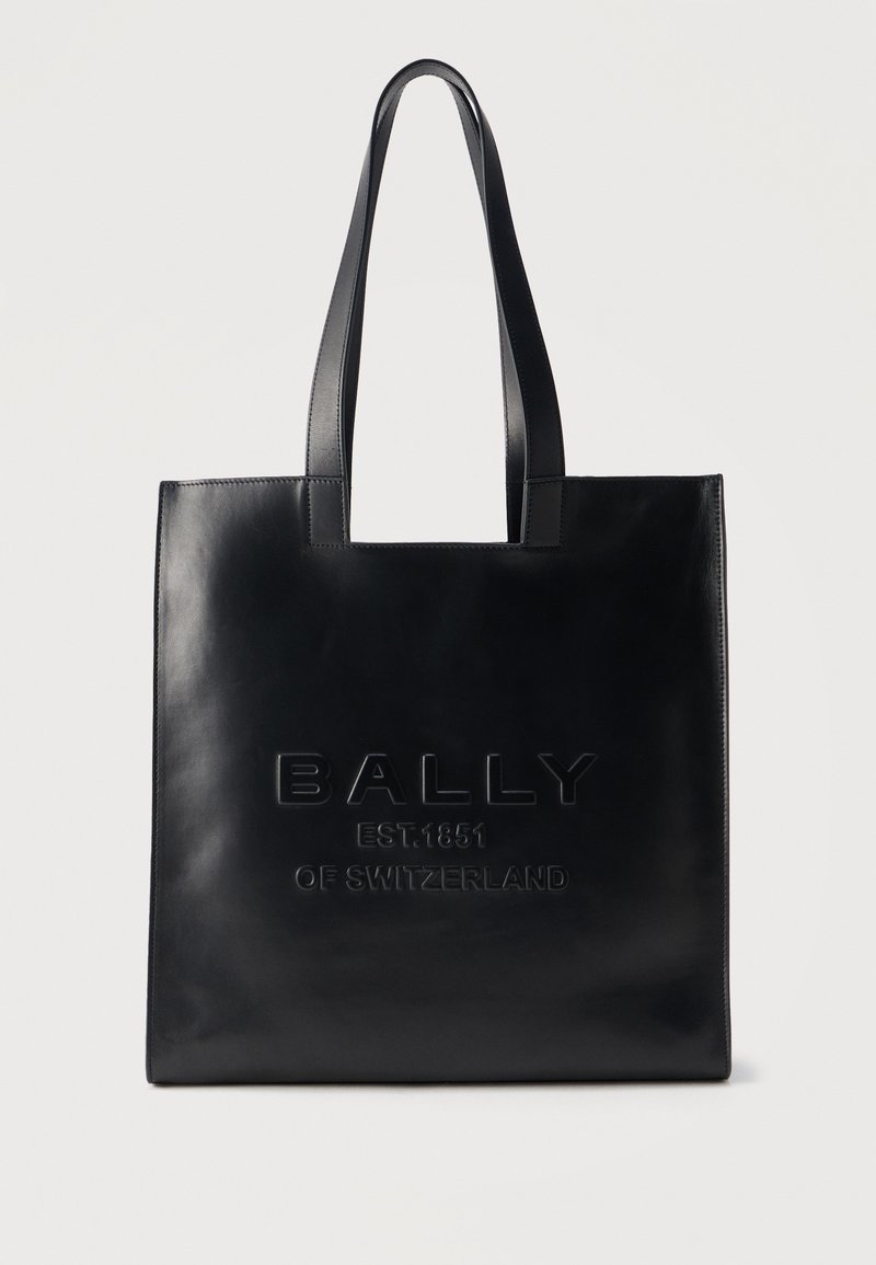 Sac fourre-tout en cuir noir avec deux longues poignées et texte embossé "BALLY EST.1851 DE SUISSE" au centre avant.