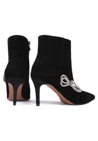 Černé semišové kotníkové boty s špičatou špičkou a stiletto podpatky. Mají dekorativní akcent v podobě kamínkového mašličky na boku a boční zip.