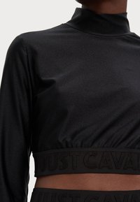 Black crop top with a high collar, made of smooth fabric. Features a textured waistband with "JUST CAVALLI" embossed. Compact design.
