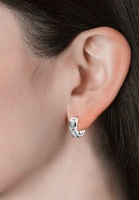Boucle d'oreille en argent avec une surface texturée ornée de cristaux transparents, en forme ovale et avec une finition polie.