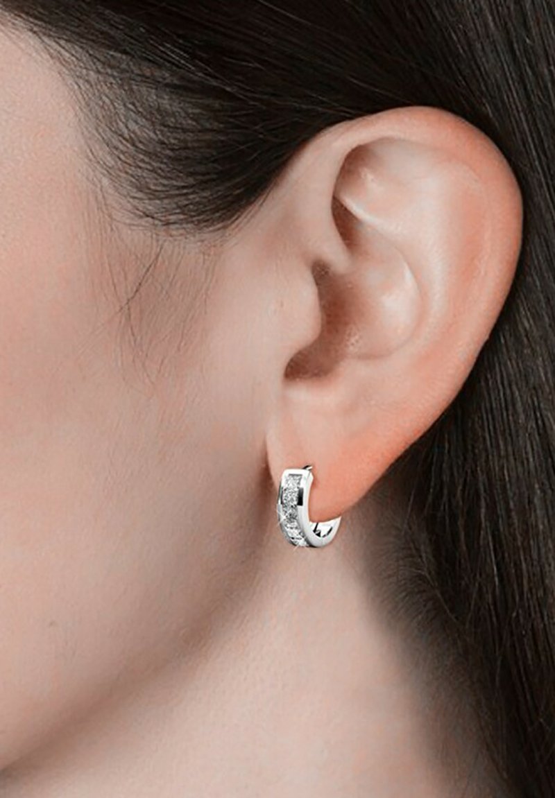 Boucle d'oreille en argent avec une surface texturée ornée de cristaux transparents, en forme ovale et avec une finition polie.