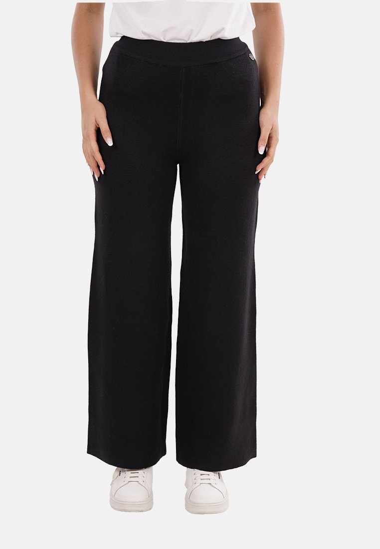 Pantaloni neri a gamba larga con elastico in vita, realizzati in tessuto morbido, caratterizzati da una superficie liscia e da un minimo di dettagli.