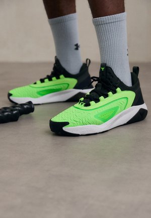 Sport shoes featuring a bright neon green upper, black accents, textured sole, and detailed design elements. Worn with grey crew socks.