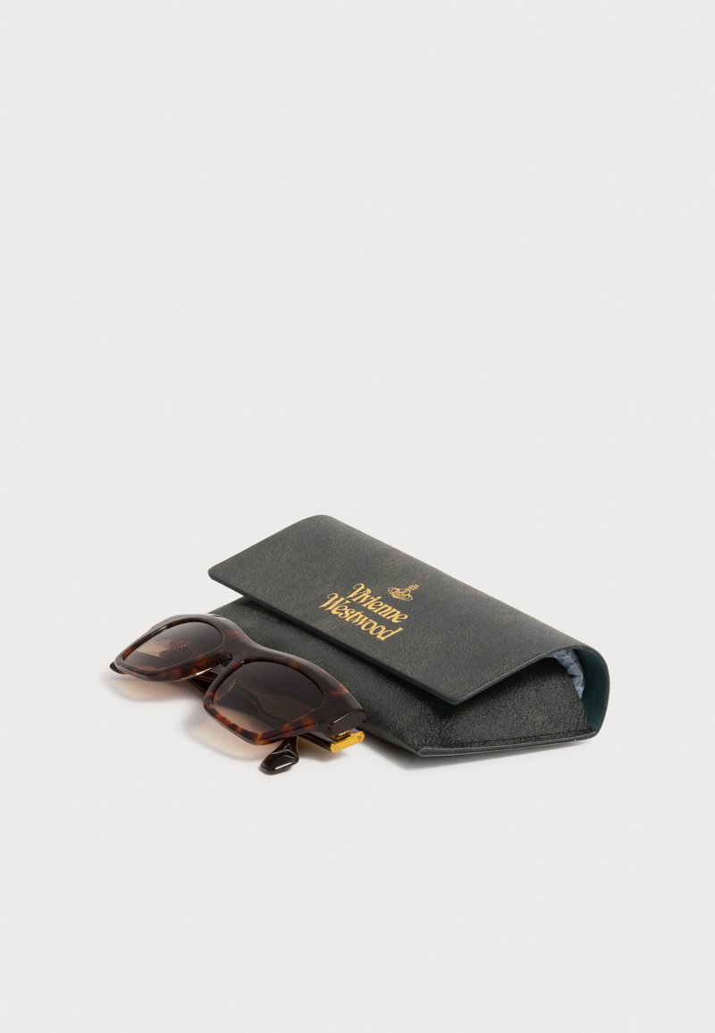 Tortoiseshell sunglasses with dark lenses resting beside a black Vivienne Westwood case with gold logo lettering.