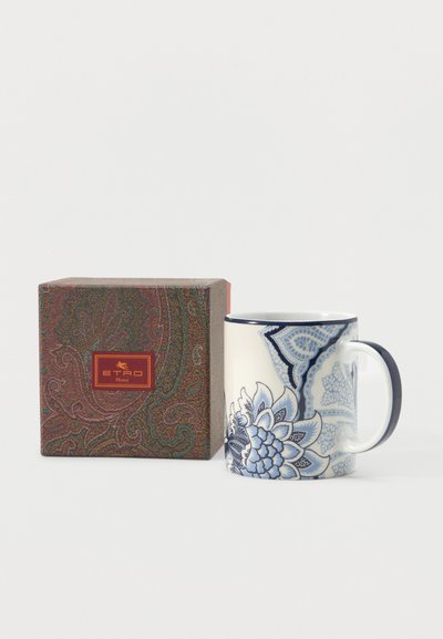 Tasse en céramique avec motif floral bleu et anse foncée à côté d'une boîte au motif cachemire étiquetée "ETRO Home" sur fond blanc.