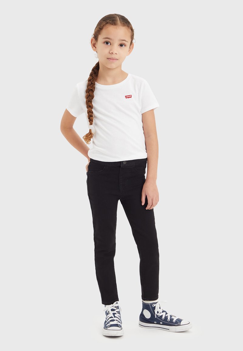 T-shirt blanc avec logo rouge Levi's, jean skinny noir et baskets montantes bleues avec accents blancs. Tenue simple et décontractée pour enfants.