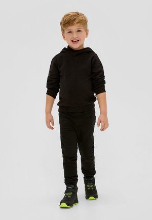 Zwarte hoodie, zwarte broek en zwarte schoenen met neongroene accenten. De hoodie heeft een zachte stof, terwijl de broek een slim fit heeft.