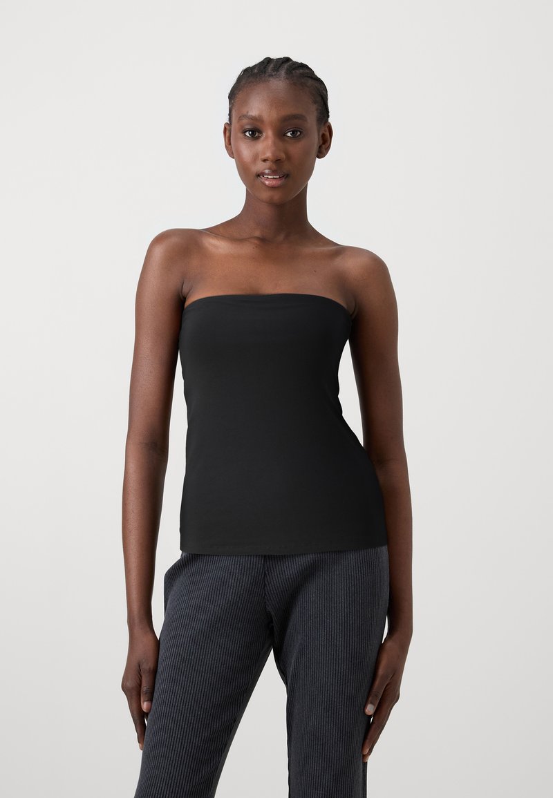 Czarny bezrękawnik z elastycznego materiału, dopasowany krój bez szwów, zestawiony z ciemnymi spodniami w pionowe paski, gładka tekstura, prosty styl.