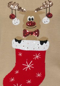 Roter Weihnachtsstrumpf mit einem gestalteten Rentier aus Pailletten, auf einem beigen Hintergrund, mit einem weißen Fellrand und dekorativen Schneeflocken in Weiß.