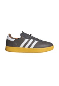 Chaussures de sport grises avec des rayures blanches, semelle en caoutchouc jaune et intérieur orange à motif. Elles présentent des lacets et une languette en maille pour la ventilation.