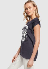 Mørkegrå T-shirt med korte ærmer og rund halsudskæring, med et hvidt kranietgrafik og tekstdesign på forsiden.