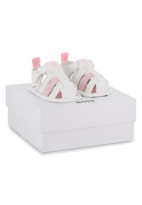 Λευκά δερμάτινα σανδάλια με ροζ λεπτομέρειες, με ανοιχτό δάχτυλο, πολλαπλές ρίγες και λουράκι στο πίσω μέρος. Παρουσιάζονται πάνω σε ένα λευκό κουτί με την ετικέτα "BOSS".
