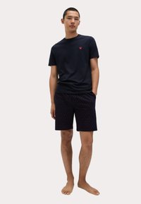 Marineblaues T-Shirt mit rotem Herz-Logo und gemusterten marineblauen Shorts mit kleinen roten Punkten. Lässige, leichte Baumwollkleidung.