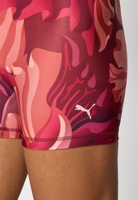 Shorts Puma dans un motif abstrait multicolore de rouges et de roses. Présente un logo blanc et un tissu lisse et extensible.