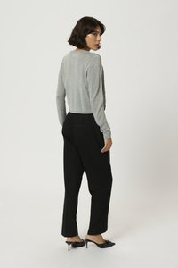 Gray, long-sleeve, lightweight top with a fitted waist, paired with loose black trousers and black heeled mules.