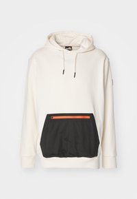 Sudadera color crema con cordones y un gran bolsillo frontal negro que incluye un compartimento con cremallera naranja.