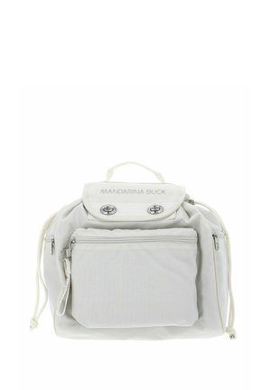 Sac à dos en tissu blanc à forme arrondie, équipé d'une poignée supérieure, d'une poche avant zippée et d'accents métalliques argentés. Logo sur le rabat.