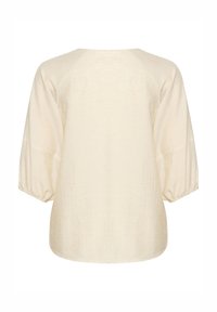 Blusa color crema realizzata in tessuto leggero. Caratterizzata da maniche raglan con polsini elasticizzati e orlo arrotondato. Texture semplice.