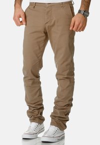 Beige cotton pants with a regular fit, featuring back pockets, belt loops, and a button closure, paired with white sneakers.