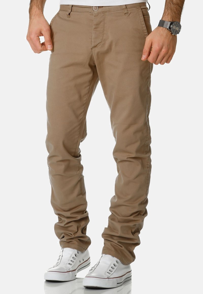 Beige cotton pants with a regular fit, featuring back pockets, belt loops, and a button closure, paired with white sneakers.