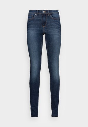 Donkerblauwe slim-fit denim jeans met voorzakken, knoopsluiting en lichte vervaging op de dijen en knieën, getoond op een witte achtergrond.