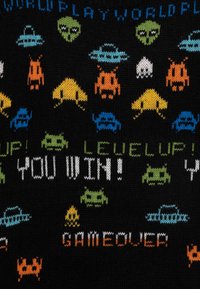 Pletený svetr s černým pozadím a barevnými retro videohrovými postavami a texty: "VYHRÁL JSI!" a "KONEC HRY" v pixelovém písmu.